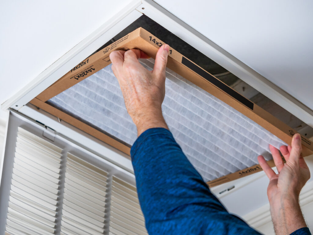 HVAC technician replacing a home air filter in Downey