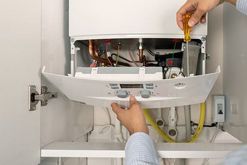 Heating technician repairing a residential boiler in Downey