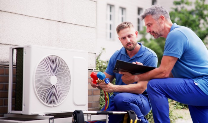 HVAC technicians installing an outdoor air conditioning unit in Downey